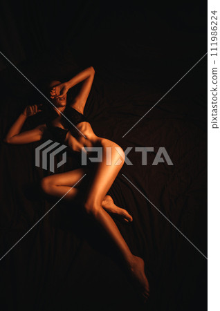 Sexy naked young girl woman with slender body in bra lying on bed in bedroom Sexy naked young girl woman with slender body in bra lying on bed in bedroom 111986224