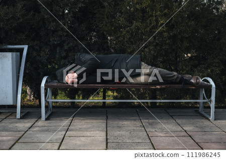 lonely man homeless and upset lies sleeping on park bench lonely man homeless and upset lies sleeping on park bench 111986245