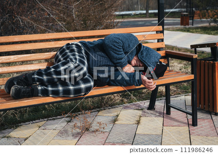 homeless dirty elderly old Caucasian man lies sleeping on park bench in autumn homeless dirty elderly old Caucasian man lies sleeping on park bench in autumn 111986246