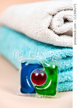 Laundry pod on beige background with soft towels Laundry pod on beige background with soft towels 111986271