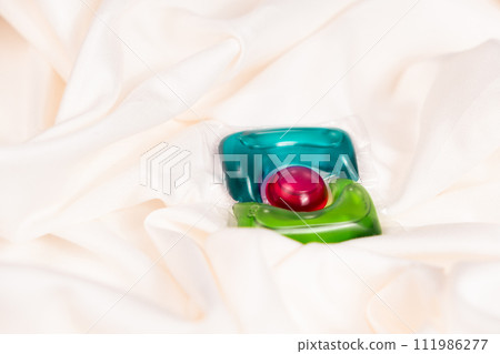 Liquid detergent gel in capsule on fabric close-up, space for text 111986277