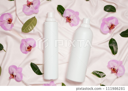 Liquid laundry detergent and fabric softener on bedding, orchid flowers, top view 111986281