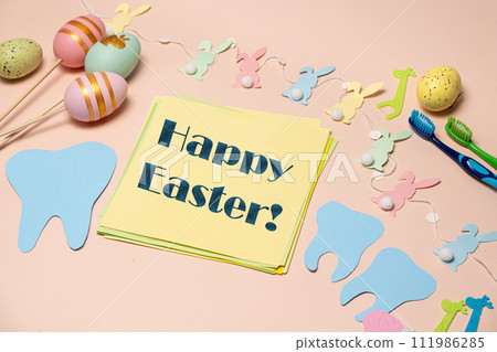 Greeting card for dentistry happy Easter text, tooth, painted eggs and bunnies top view. Greeting card for dentistry happy Easter text, tooth, painted eggs and bunnies top view. 111986285