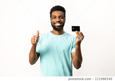 Happy African American Man Holding Credit Card and Giving Thumbs Up Happy African American Man Holding Credit Card and Giving Thumbs Up 111986540