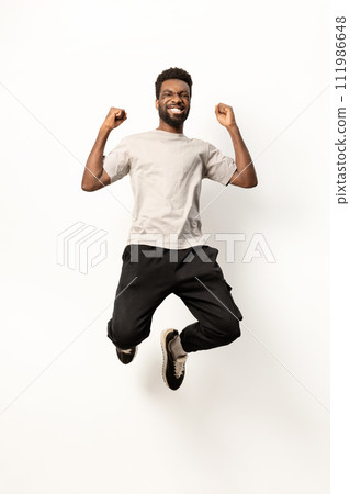 Joyful African American Man Jumping with Excitement in Studio 111986648