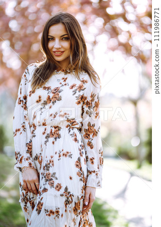 Beautiful young woman near the blooming spring tree. Attractive girl enjoying her time outside in park. 111986771