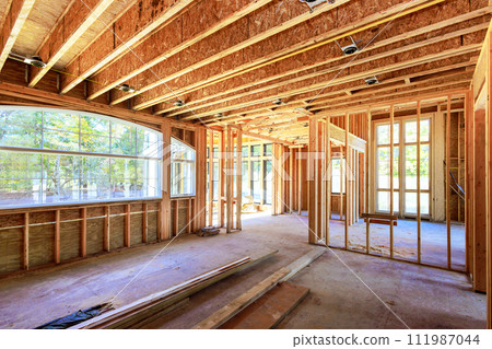 New home is being built at building area with unfinished framing beams wooden home in construction phase 111987044
