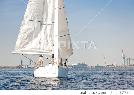Racing yacht with white sails in a calm sea 111987734
