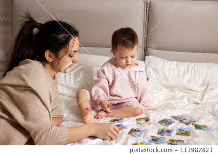 pretty mother playing puzzle together with her little child girl in bedroom pretty mother playing puzzle together with her little child girl in bedroom 111987821