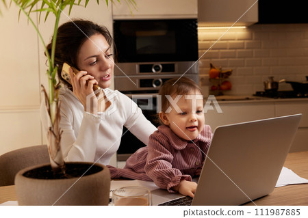 happy businesswoman working at home with her little child girl. woman talking on the phone 111987885