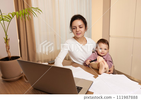 beautiful businesswoman working at home with her little child daughter. Stay at home beautiful businesswoman working at home with her little child daughter. Stay at home 111987888