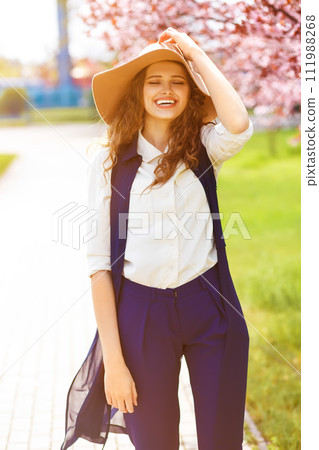 Outdoor portrait of young beautiful fashionable lady posing near flowering tree. Outdoor portrait of young beautiful fashionable lady posing near flowering tree. 111988268