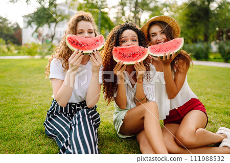 Three young woman have fun together and eating watermelon in hot summer day. 111988532