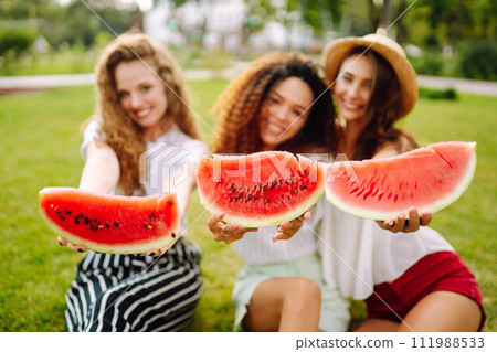 Three young woman have fun together and eating watermelon in hot summer day. 111988533
