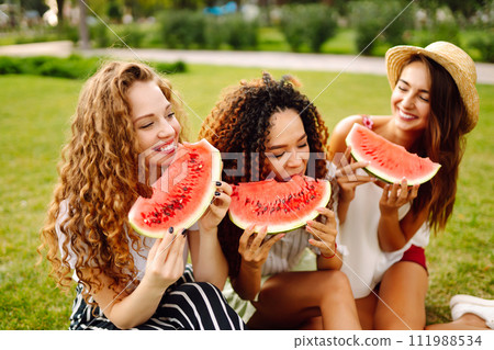 Three young woman have fun together and eating watermelon in hot summer day. 111988534
