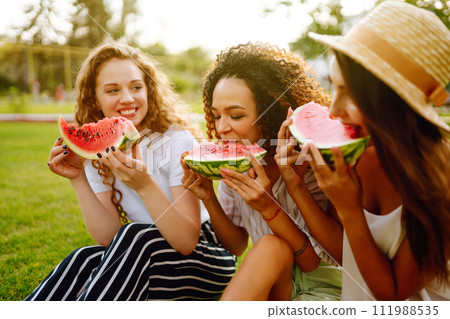 Three young woman have fun together and eating watermelon in hot summer day. 111988535