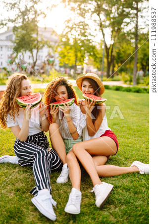 Three young woman have fun together and eating watermelon in hot summer day. 111988537