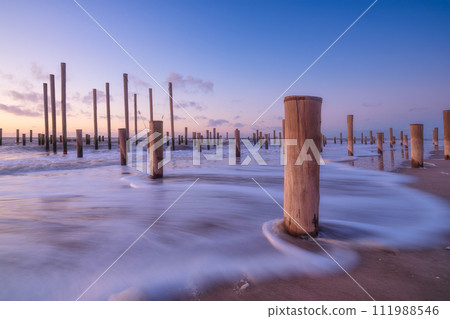 A seascape during sunset. Pillars on the seashore. Bright sky during sunset. A seascape during sunset. Pillars on the seashore. Bright sky during sunset. 111988546
