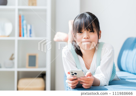 An elementary school girl operating a smartphone. 111988666