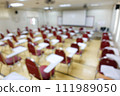 Blurred abstract background of examination room with undergraduate students inside. Blurred view of a student doing the final test in the exam room. Blurry view of study chairs in university. 111989050