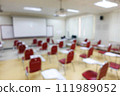 Blurred abstract background of examination room with undergraduate students inside. Blurred view of a student doing the final test in the exam room. Blurry view of study chairs in university. 111989052