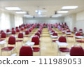 Blurred abstract background of examination room with undergraduate students inside. Blurred view of a student doing the final test in the exam room. Blurry view of study chairs in university. 111989053