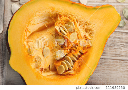 pumpkin and pumpkin seeds cut in half on a wooden background 111989230