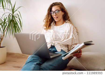 Young woman sits at home, learning preparing for exam using literature laptop, concept of knowledge. Young woman sits at home, learning preparing for exam using literature laptop, concept of knowledge. 111989393
