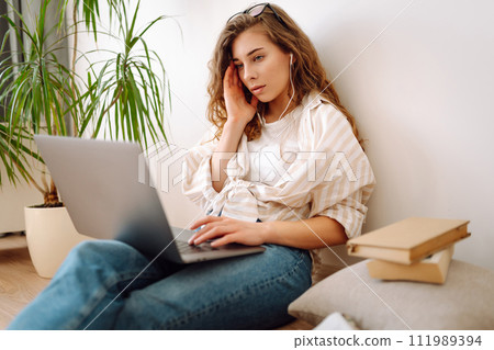 Young woman sits at home, learning preparing for exam using literature laptop, concept of knowledge. Young woman sits at home, learning preparing for exam using literature laptop, concept of knowledge. 111989394