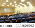 blurred or defocused people in the seminar convention hall. Business meeting for a press conference or lecturer education concept with a wide view from the room's corner. Modern, blurry auditorium. 111989592