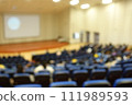 blurred or defocused people in the seminar convention hall. Business meeting for a press conference or lecturer education concept with a wide view from the room's corner. Modern, blurry auditorium. 111989593