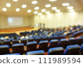 blurred or defocused people in the seminar convention hall. Business meeting for a press conference or lecturer education concept with a wide view from the room's corner. Modern, blurry auditorium. 111989594