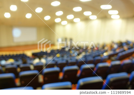 blurred or defocused people in the seminar convention hall. Business meeting for a press conference or lecturer education concept with a wide view from the room's corner. Modern, blurry auditorium. blurred or defocused people in the seminar convention hall. Business meeting for a press conference or lecturer education concept with a wide view from the room's corner. Modern, blurry auditorium. 111989594