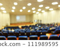 blurred or defocused people in the seminar convention hall. Business meeting for a press conference or lecturer education concept with a wide view from the room's corner. Modern, blurry auditorium. 111989595
