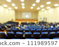 blurred or defocused people in the seminar convention hall. Business meeting for a press conference or lecturer education concept with a wide view from the room's corner. Modern, blurry auditorium. 111989597