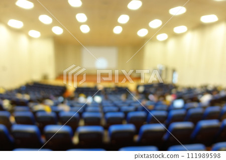 blurred or defocused people in the seminar convention hall. Business meeting for a press conference or lecturer education concept with a wide view from the room's corner. Modern, blurry auditorium. blurred or defocused people in the seminar convention hall. Business meeting for a press conference or lecturer education concept with a wide view from the room's corner. Modern, blurry auditorium. 111989598