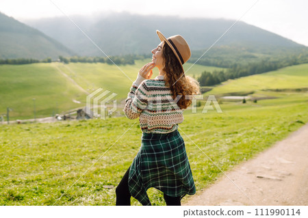 Happy female traveler exploring area in green valley with mountains in background. Concept of nature 111990114