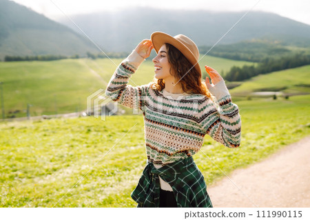 Happy female traveler exploring area in green valley with mountains in background. Concept of nature 111990115