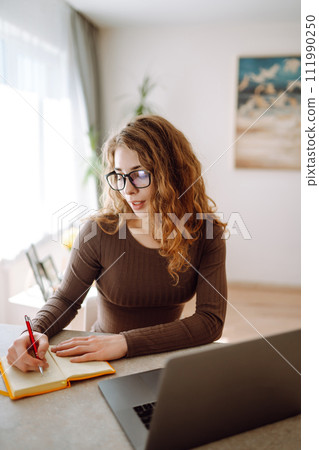 Businesswoman using laptop wearing glasses while sitting at workplace at home. Freelance concept. Businesswoman using laptop wearing glasses while sitting at workplace at home. Freelance concept. 111990250