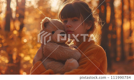 Beautiful young woman with teddy bear in the autumn forest. 111990784