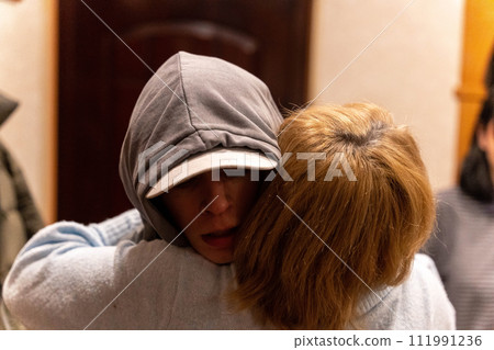 Emotional moment, teenage son hugging mother goodbye before army deployment 111991236