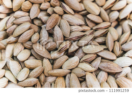 Heap of unpeeled almonds in shells - natural organic nut background Heap of unpeeled almonds in shells - natural organic nut background 111991259