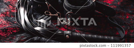 set of BDSM sex toys with handcuffs and whip flogger for submission and domination on a black background 111991357