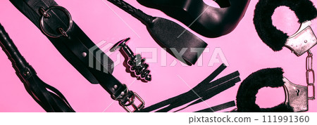 set of BDSM sex toys with handcuffs, whip flogger, butt anal plug for submission and domination on a pink background set of BDSM sex toys with handcuffs, whip flogger, butt anal plug for submission and domination on a pink background 111991360