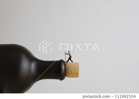 Closeup of a miniature worker opening a bottle Closeup of a miniature worker opening a bottle 111992524