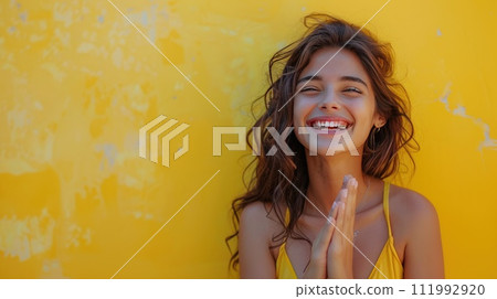 A beautiful young woman happily claps her hands, laughs and looks at the camera 111992920