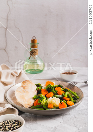 Mixed vegetables and steamed chicken breast on a plate on the table vertical view Mixed vegetables and steamed chicken breast on a plate on the table vertical view 111993762