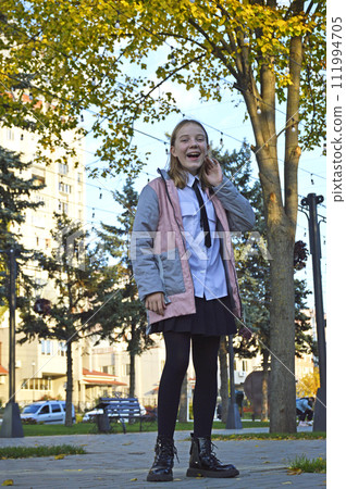 A beautiful girl walks in the autumn park, the child smiles and laughs A beautiful girl walks in the autumn park, the child smiles and laughs 111994705