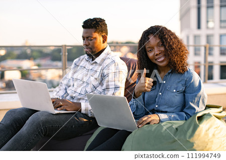 African colleagues working with laptops while sitting at beanbags. African colleagues working with laptops while sitting at beanbags. 111994749