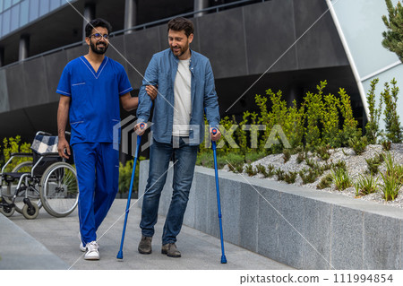 Man with sticks walking with a male nurse 111994854